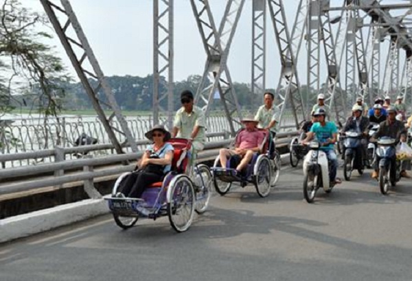 Tourist traveling by Xich Lo on Truong Tien Bridge